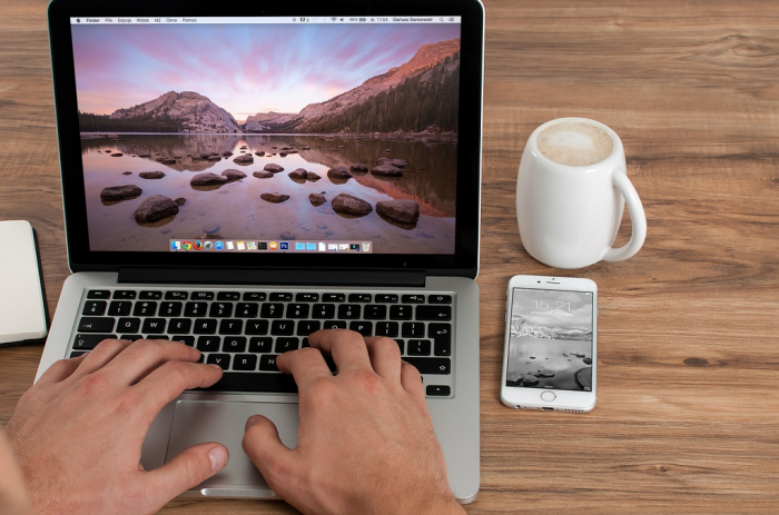 working on laptop with phone and coffee